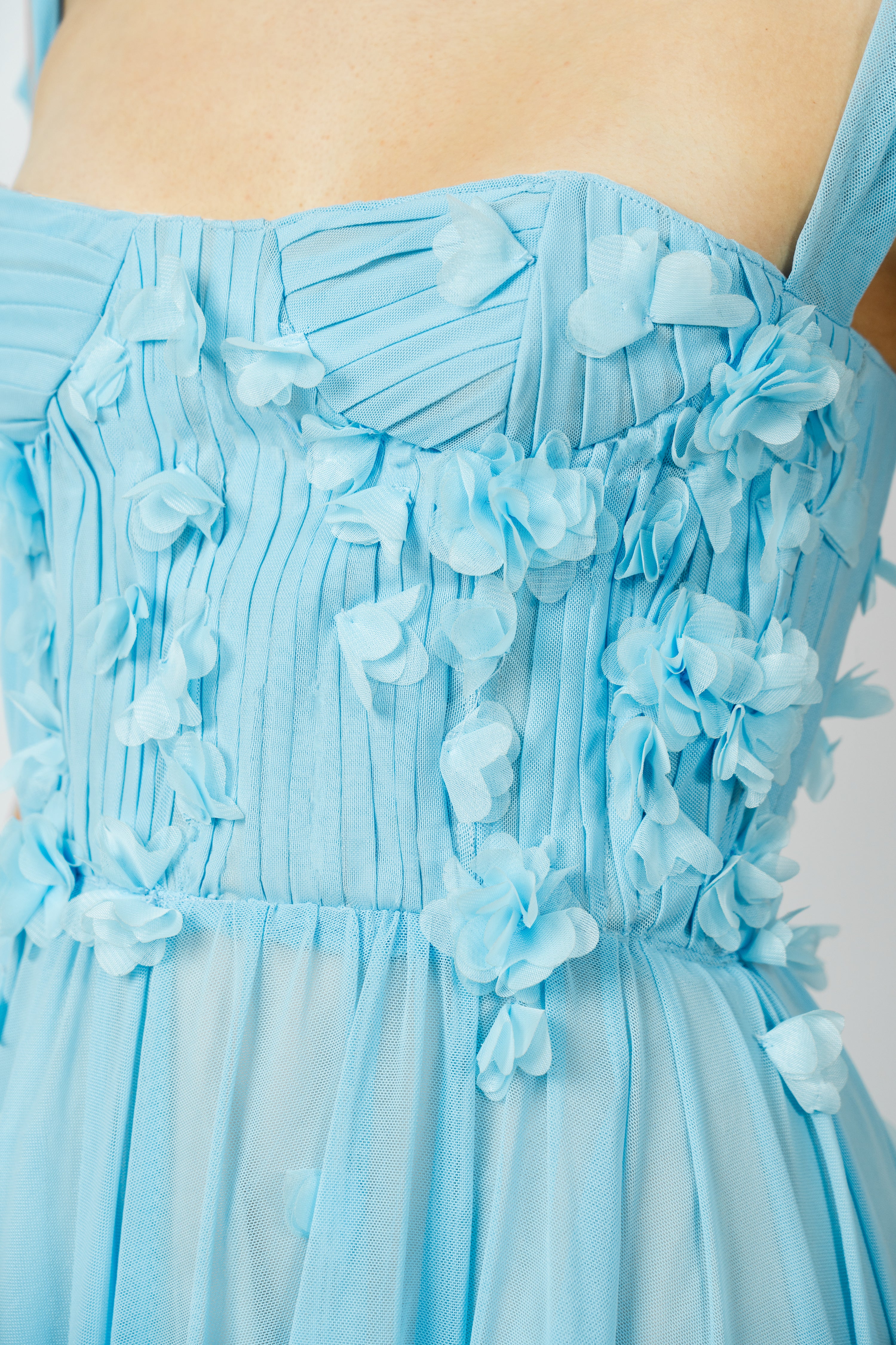 Close-up of a light blue dress with floral details on a plain background