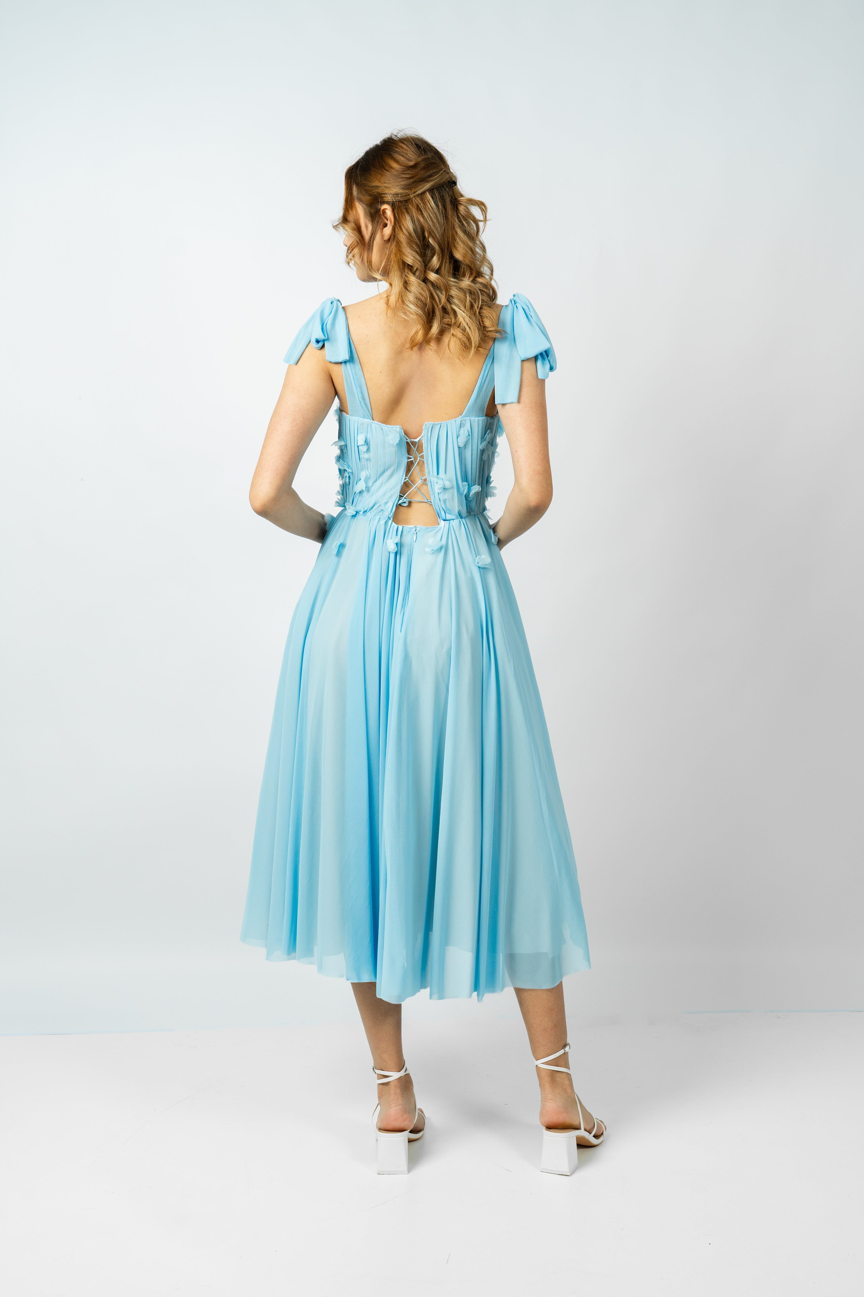 Woman wearing a light blue dress with a backless design on a white background