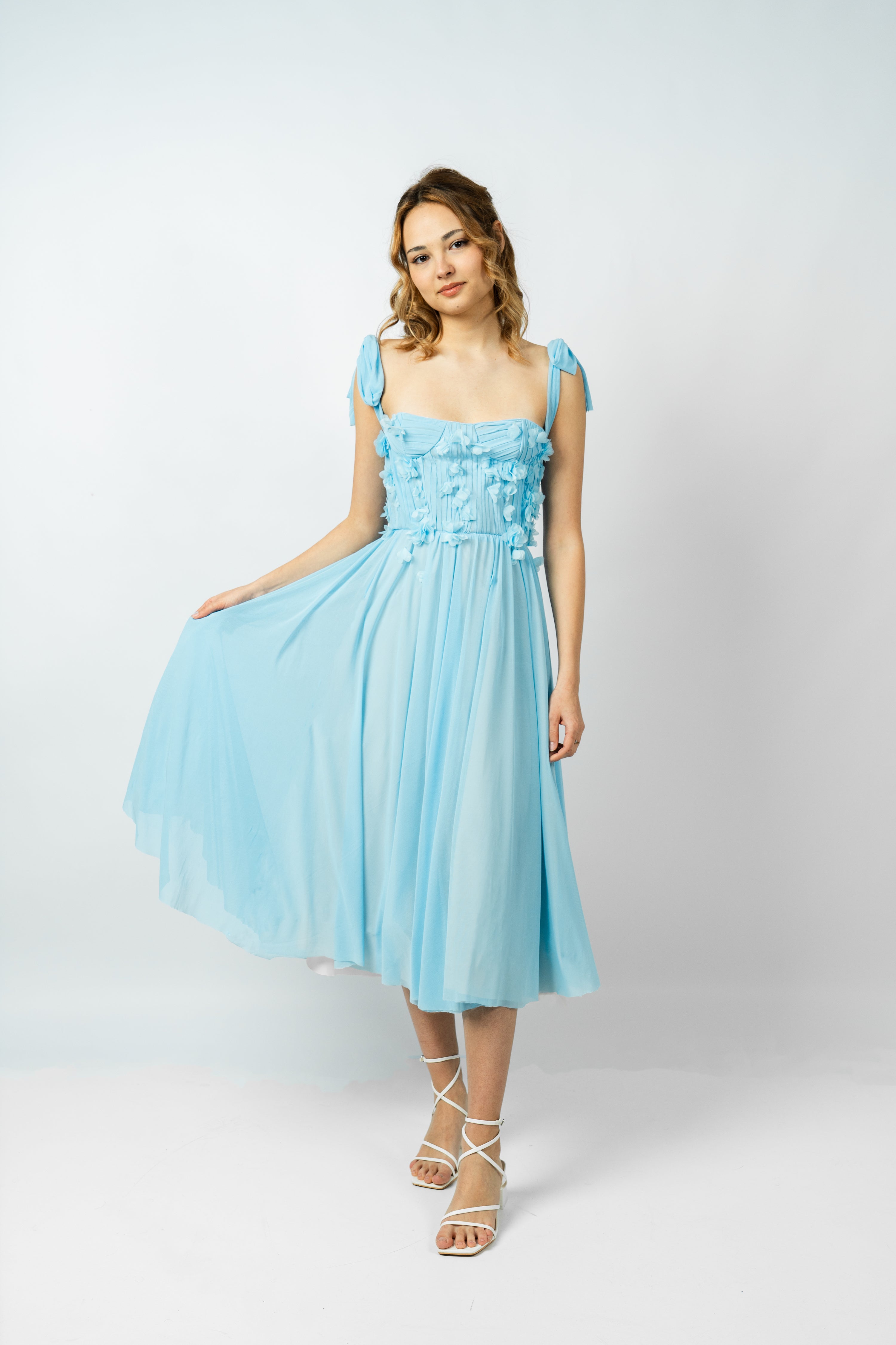 Woman wearing a light blue dress with floral details on a white background