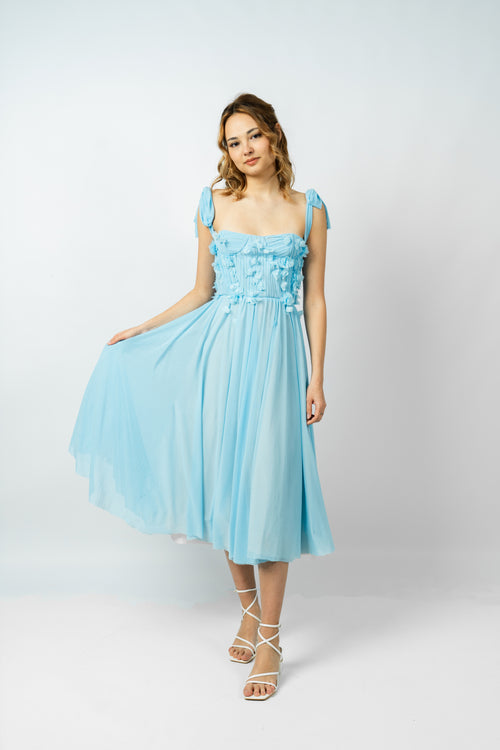 Woman wearing a light blue dress with floral details on a white background