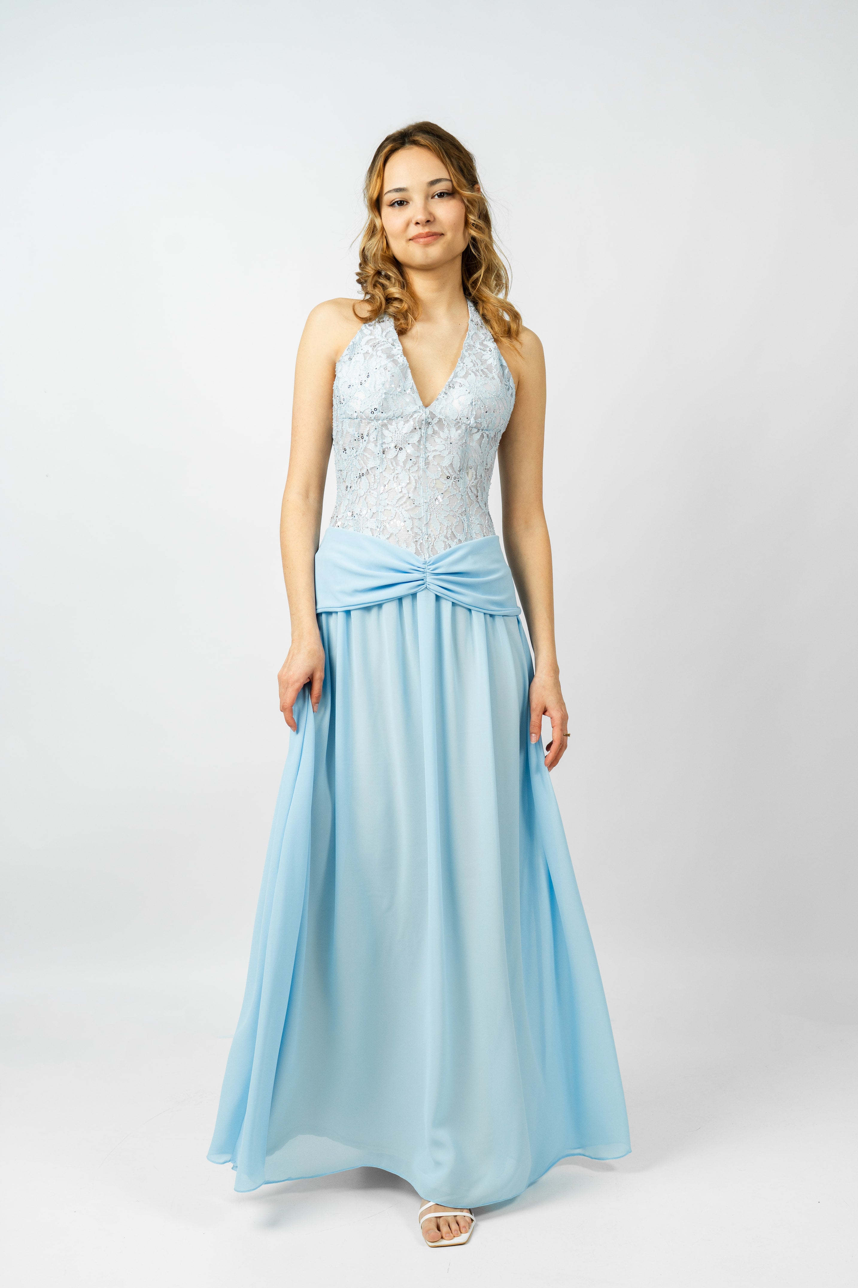 Woman wearing a light blue evening gown with a white top on a white background