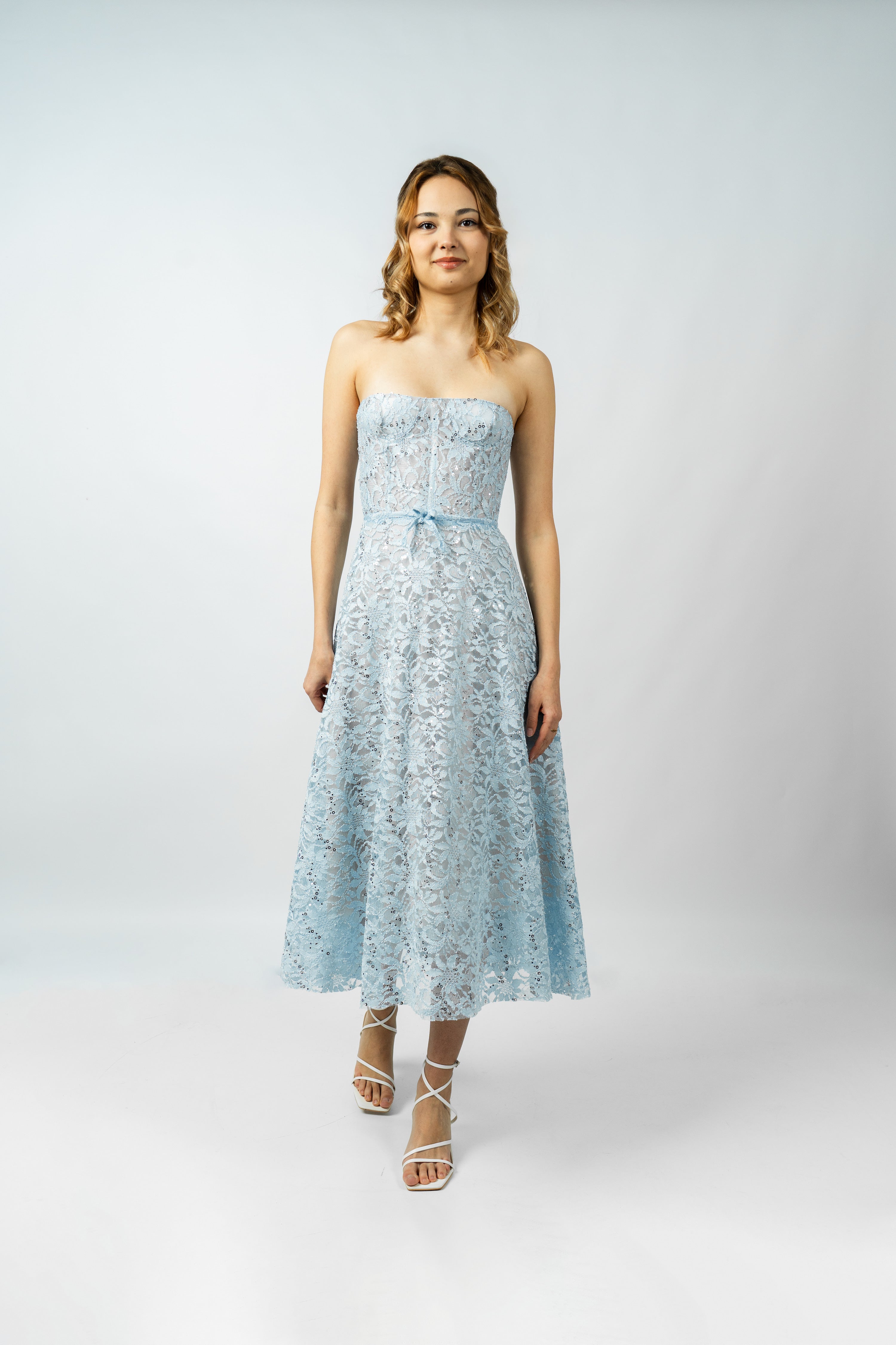 Woman wearing a light blue strapless dress on a white background
